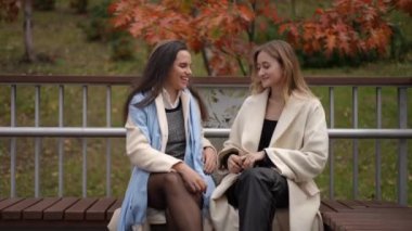 İki neşeli ve mutlu arkadaş güler ve güzel bir sonbahar parkı ortamında birbirlerine eşlik ederler.