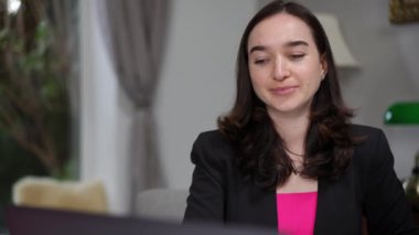 Siyah ceketli ve pembe bluzlu bir beslenme uzmanı elinde beyaz bir takviye şişesiyle bir video konferansında gülümsüyor. Sağlıktan bahsederken üründen memnun görünüyor.