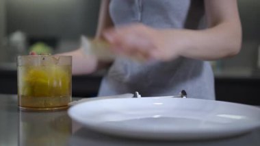 Bir insan eli, servis yapmaya hazır bir kavanoz turunçgil meyvesine uzanır. Parlak ve ferahlatıcı mutfak atmosferi.