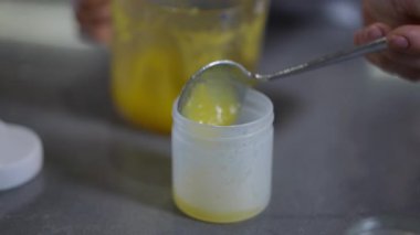 Parlak sarı sıvı madde ile kısmen doldurulmuş şeffaf bir kabın yakın görüntüsü