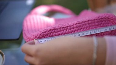 Yansıtıcı bir yüzeyde sergilenen canlı pembe bir örgü çantası. Moda ve DIY hayranları için mükemmel..