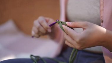 Mor bir örgü kancası kullanarak canlı yeşil bir iplikle ustalıkla el örgüsü yaparken çekilmiş yakın plan bir fotoğraf.