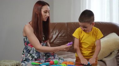 Bir çocuk ve bakıcı arasındaki renkli modelleme bileşimiyle neşeli bir yaratıcılık oturumu.