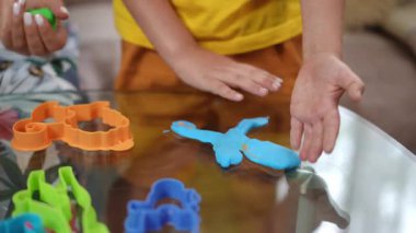 Çocuklar çeşitli kurabiye kesicilerle deneyler yaparken renkli hamurlarla eğleniyorlar.