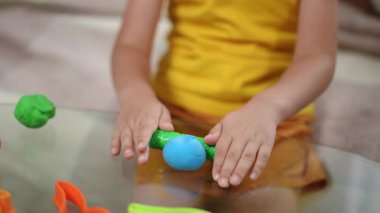 Bir çocuk yaratıcı ve yaratıcı oyunlarla aktif olarak meşgul olur. Yaratıcılığını arttırmak için renkli killeri şekillendirir.