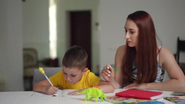 Yetiştiren bir anne çocuğuna yaratıcı bir sanat oturumunda rehberlik eder, tecrübe boyunca öğrenmeyi teşvik eder.