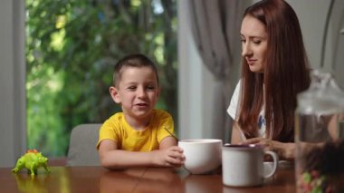 Bir anne ve küçük oğlu evlerinde rahat bir anın tadını çıkarıyorlar. Yeşilliklerle çevrili rahatlatıcı içkilerle.