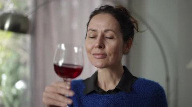 Kırmızı şarabın tadını çıkaran bir kadın, enfes tadını yansıtıyor sıcak, şık, rahat bir yerde.