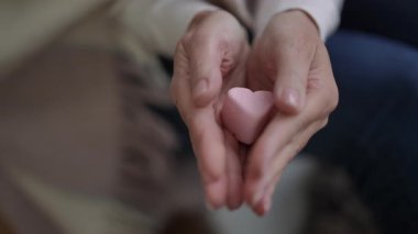 Nazik, nazik bir jest pembe bir lokum kalbi tutan iki el sevgi ve nezaketi güzel bir şekilde sembolize ediyor.