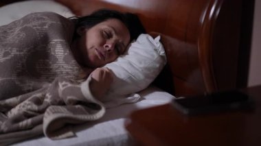 Sıcak ve davetkar yatağında uyanan bir kadın rahat bir sabahta cep telefonuna uzanır.