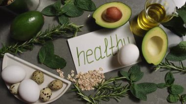 Besleyici tarifler için avokado, yumurta ve şifalı bitkiler içeren sağlıklı malzemelerin canlı bir koleksiyonu..