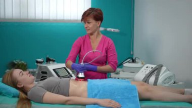 Yetenekli bir pratisyen, modern bir güzellik stüdyosundaki bir müşteriye vücut hatlarıyla ilgili bir tedavi uyguluyor.