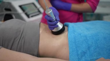 Kozmetik uzmanının kadın karnına invazif olmayan ultrason boşaltımı prosedürü uyguladığı yakın çekim. Profesyonel estetik bir ortamda vücut şekillendirme oturumu.