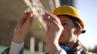 Tam güvenlik teçhizatı kullanan bir kadın, güvenlik önlemlerinin önemli bir rol oynadığını vurgulayarak işe hazırlanıyor.