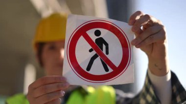 İnşaat işçisi, inşaat sahasında yasak giriş olduğunu belirten yaya levhası göstermiş.