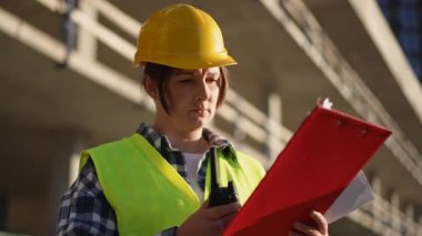 Yetenekli bir inşaat işçisi telsiz aracılığıyla etkin iletişim kurarken alan güvenliğini sağlar.