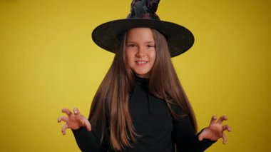 Cadı kostümü giymiş genç bir kız, tuhaf şapkasıyla, parlak bir fonda şakacı bir poz veriyor.