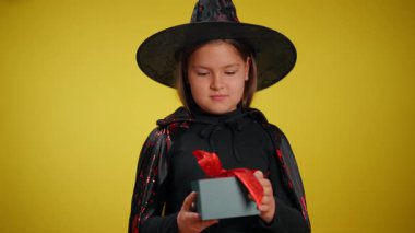 Genç bir cadı neşeyle renkli bir hediyeyi açıyor, gerçek Cadılar Bayramı ruhunu ve merakını gözler önüne seriyor.