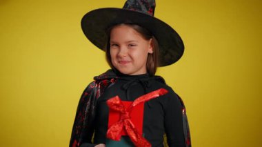 Büyük bir şapkayla birlikte renkli bir cadı kostümü giyen genç bir kız, Cadılar Bayramı şenliklerinin keyfini çıkarıyor.