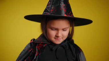 Enfes genç bir kız kaprisli bir cadı gibi giyinmiş, büyüleyici cazibesini altın bir parayla sergiliyor.