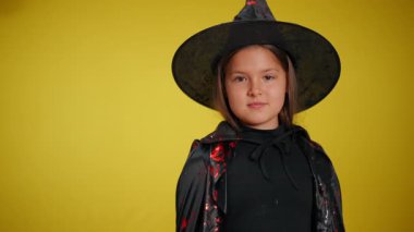 Tuhaf bir cadı kostümü giymiş genç bir kız neşeli ve neşeli bir şekilde poz veriyor.