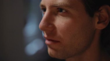 Derin düşüncelere dalmış, benzersiz özelliklerini ve ifadesini güzelce sergileyen genç bir adamın yakın plan portresi.