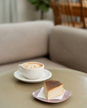 Keyifli bir öğleden sonra, sıcak bir kafede bir dilim cheesecake ve bir fincan latte içiyorum.