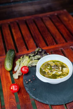 Taze salatayla servis edilen balıklı sebze çorbası.