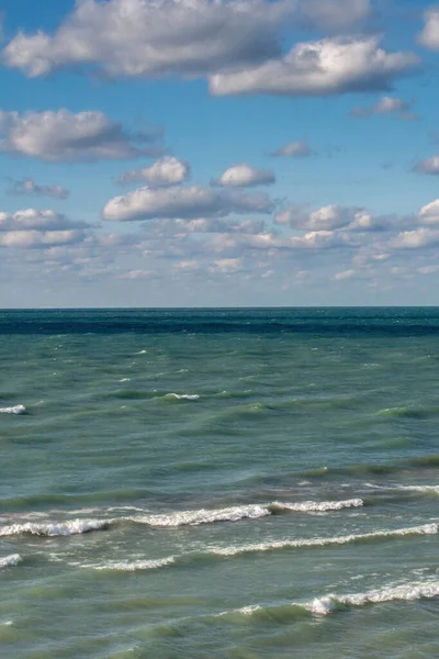 Beautiful waters in blues and greens with a sky of puffy clouds, shows a wonderful day on Lake Michigan in Michigan USA