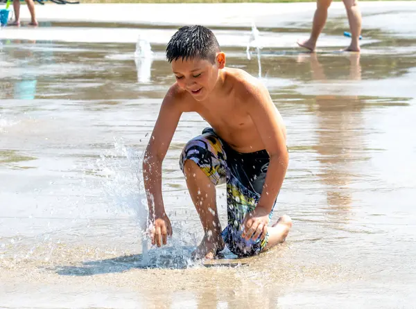 stock image Happy boy cools off and splashes in this urban fountain