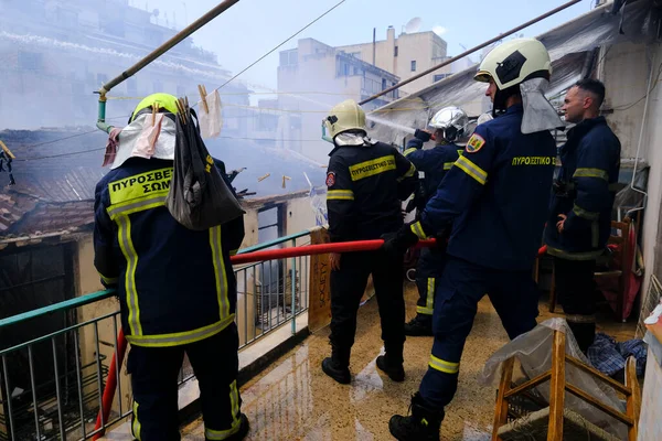 消防士達は 2022年8月17日にギリシャのアテネ中央部の放棄された建物で火災を消火しようとします — ストック写真