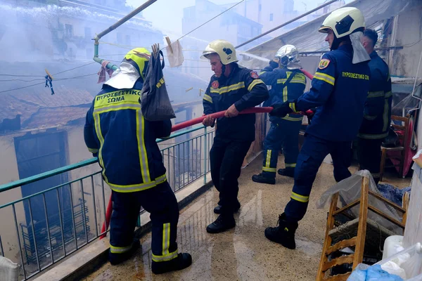 消防士達は 2022年8月17日にギリシャのアテネ中央部の放棄された建物で火災を消火しようとします — ストック写真