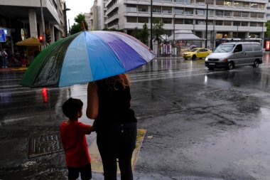 Yunanistan 'ın başkenti Atina' da 23 Ağustos 2022 'de meydana gelen yağış sırasında yayalar kendilerini şemsiyelerle yağmurdan koruyorlar..