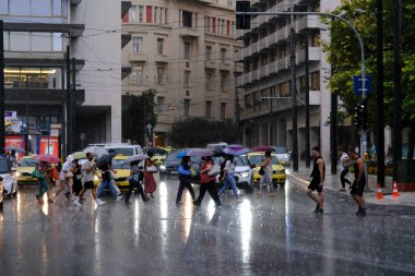 Yunanistan 'ın başkenti Atina' da 23 Ağustos 2022 'de meydana gelen yağış sırasında yayalar kendilerini şemsiyelerle yağmurdan koruyorlar..