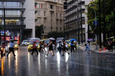 Yunanistan 'ın başkenti Atina' da 23 Ağustos 2022 'de meydana gelen yağış sırasında yayalar kendilerini şemsiyelerle yağmurdan koruyorlar..