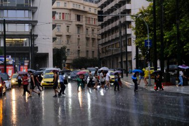 Yunanistan 'ın başkenti Atina' da 23 Ağustos 2022 'de meydana gelen yağış sırasında yayalar kendilerini şemsiyelerle yağmurdan koruyorlar..