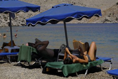 İnsanlar 30 Temmuz 2022 'de Yunanistan' ın Saint Nicholas Plajı 'nda denizin keyfini çıkarıyorlar..
