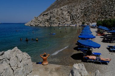İnsanlar 30 Temmuz 2022 'de Yunanistan' ın Saint Nicholas Plajı 'nda denizin keyfini çıkarıyorlar..
