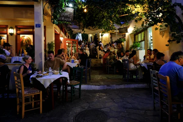 人々は2022年8月15日にギリシャのアテネのプラカ地区のカフェのテラスに座っています — ストック写真