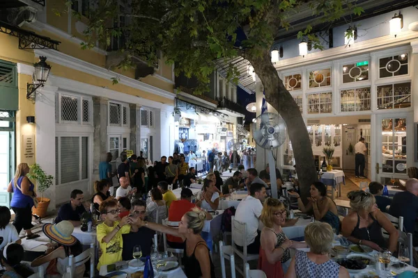 人々は2022年8月15日にギリシャのアテネのプラカ地区のカフェのテラスに座っています — ストック写真