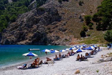 İnsanlar 1 Ağustos 2022 'de Yunanistan' ın Symi Dodecanese plajında güneş ve denizin keyfini çıkarıyorlar..