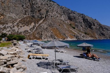 İnsanlar 1 Ağustos 2022 'de Yunanistan' ın Symi Dodecanese plajında güneş ve denizin keyfini çıkarıyorlar..
