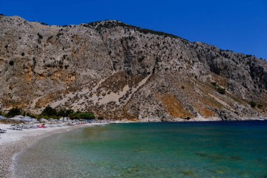 İnsanlar 1 Ağustos 2022 'de Yunanistan' ın Symi Dodecanese plajında güneş ve denizin keyfini çıkarıyorlar..
