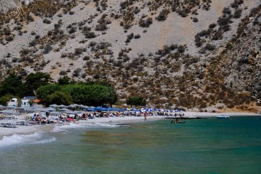 İnsanlar 1 Ağustos 2022 'de Yunanistan' ın Symi Dodecanese plajında güneş ve denizin keyfini çıkarıyorlar..