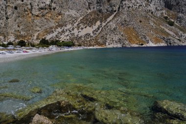 İnsanlar 1 Ağustos 2022 'de Yunanistan' ın Symi Dodecanese plajında güneş ve denizin keyfini çıkarıyorlar..