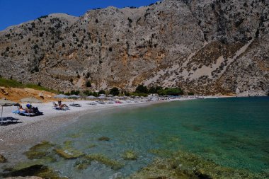 İnsanlar 1 Ağustos 2022 'de Yunanistan' ın Symi Dodecanese plajında güneş ve denizin keyfini çıkarıyorlar..