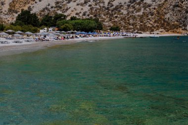 İnsanlar 1 Ağustos 2022 'de Yunanistan' ın Symi Dodecanese plajında güneş ve denizin keyfini çıkarıyorlar..