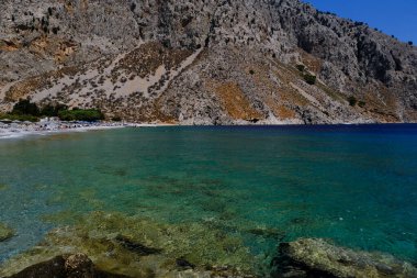 İnsanlar 1 Ağustos 2022 'de Yunanistan' ın Symi Dodecanese plajında güneş ve denizin keyfini çıkarıyorlar..