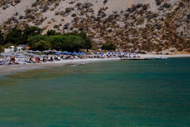 İnsanlar 1 Ağustos 2022 'de Yunanistan' ın Symi Dodecanese plajında güneş ve denizin keyfini çıkarıyorlar..
