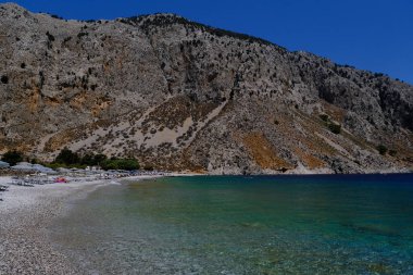 İnsanlar 1 Ağustos 2022 'de Yunanistan' ın Symi Dodecanese plajında güneş ve denizin keyfini çıkarıyorlar..